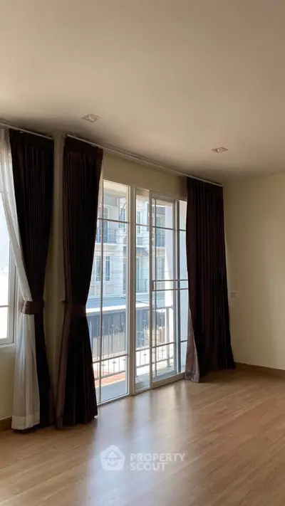 Spacious living room with large windows and elegant curtains, offering ample natural light and a modern ambiance.