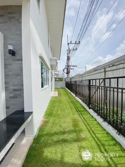 Modern exterior view of a house with lush green lawn and sleek fence design.