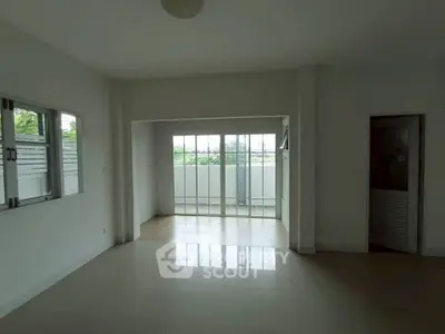 Spacious empty living room with large windows and balcony access