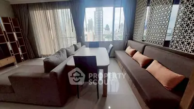 Spacious living room with modern decor and city view, featuring large windows and comfortable seating.