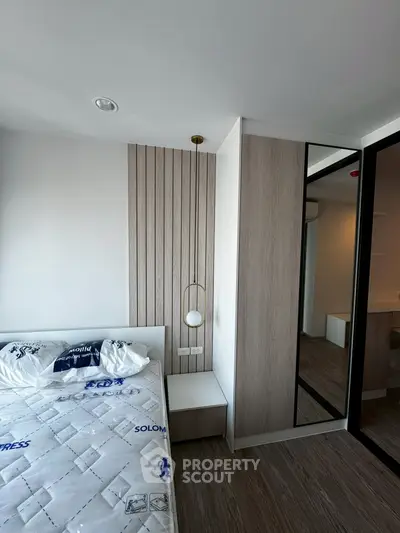 Modern bedroom with stylish wooden paneling and mirrored wardrobe