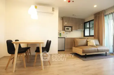 Modern open-plan living room with cozy seating and dining area, featuring sleek kitchen appliances.