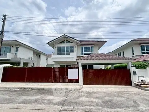 Charming two-story house with red fence and tiled roof in suburban neighborhood.