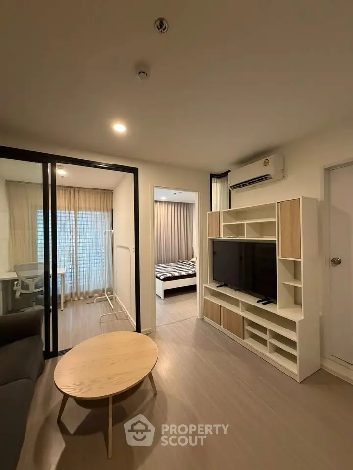 Modern living room with sleek furniture and open view into a cozy bedroom, perfect for urban living.