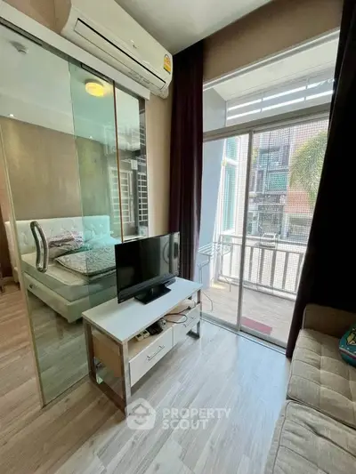 Modern bedroom with glass partition and balcony access, featuring sleek furniture and natural light.