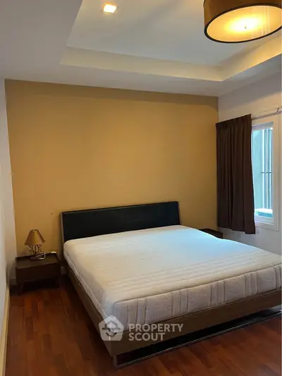 Spacious bedroom with modern design and natural light, featuring a comfortable bed and wooden flooring.