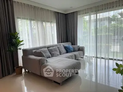 Spacious living room with modern gray sofa and large windows offering natural light.