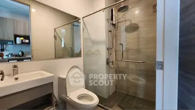 Modern bathroom with glass shower and sleek fixtures in contemporary apartment.