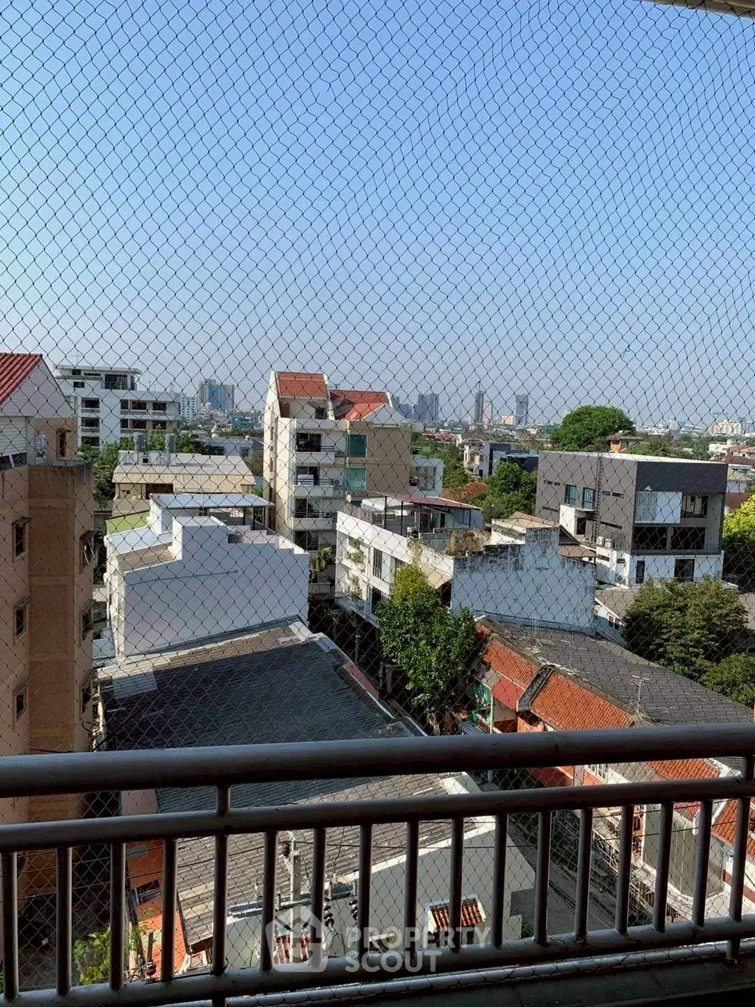 Stunning cityscape view from a high-rise balcony with safety netting, showcasing urban living.