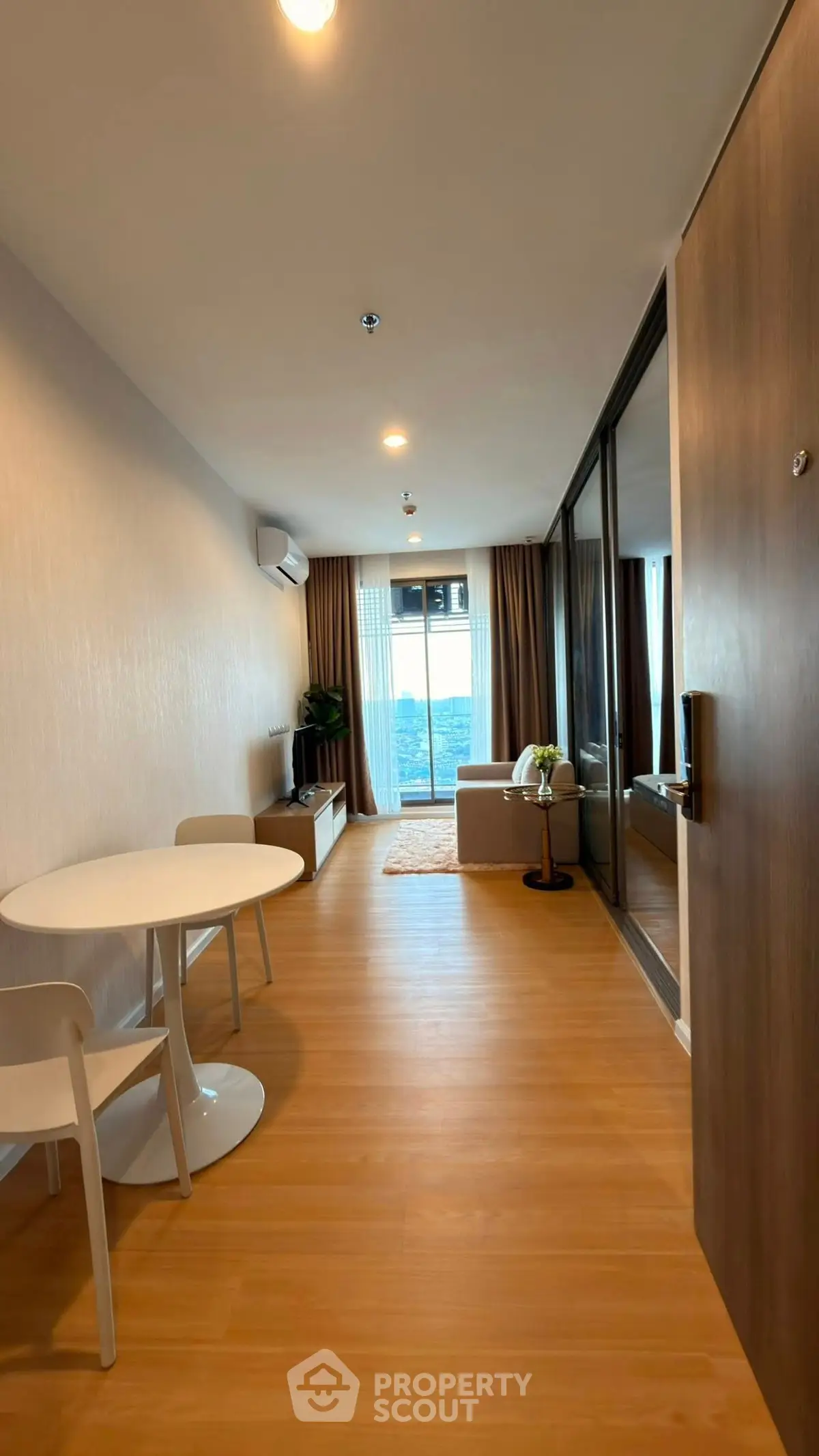 Modern living room with wooden flooring and large window offering a stunning view.