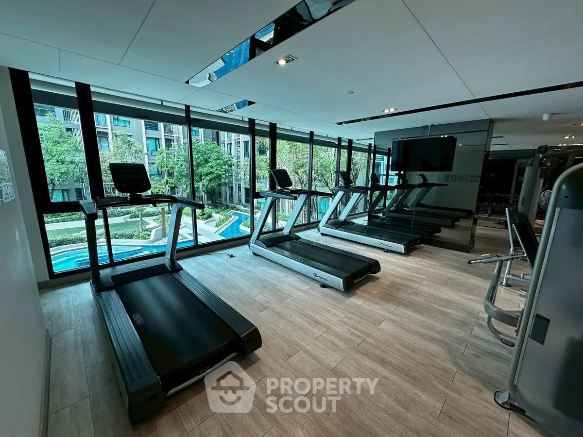 Modern gym with treadmills and pool view in luxury apartment complex