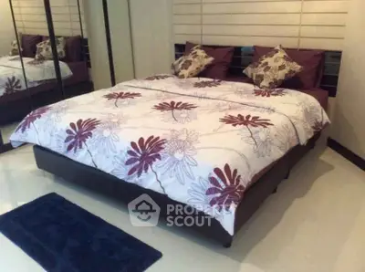 Cozy bedroom with stylish floral bedding and mirrored wardrobe in modern apartment.