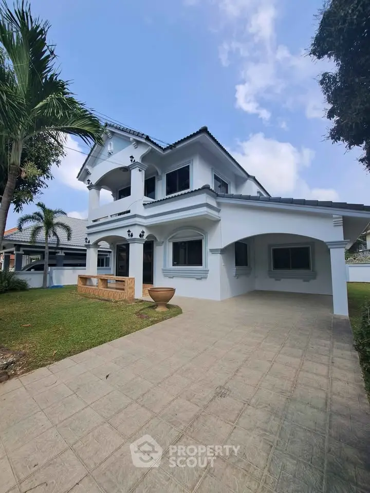 Elegant two-story white house with spacious driveway and lush garden