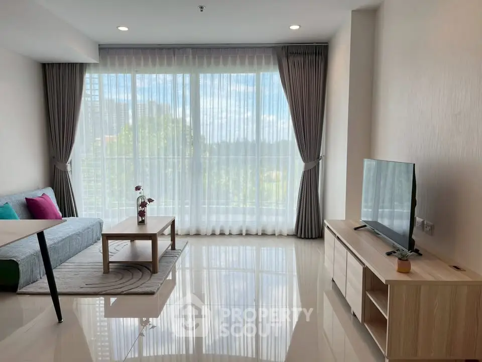 Spacious living room with large windows and modern decor in a bright apartment.