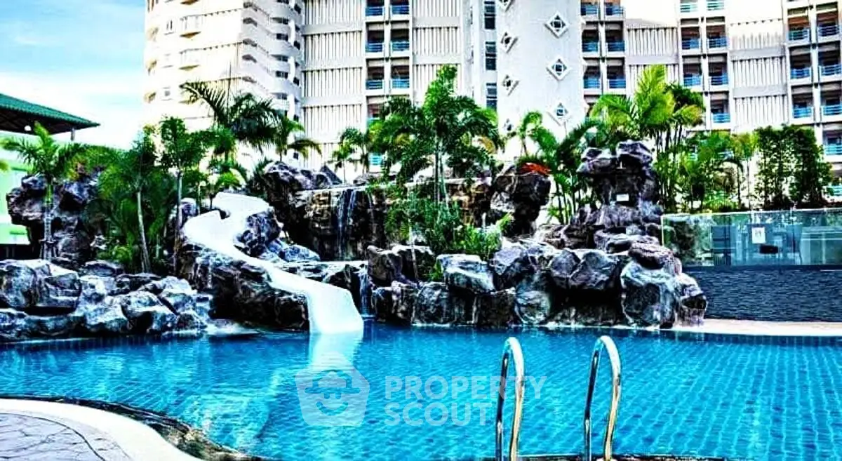 Luxurious residential pool with waterfall and lush landscaping in modern apartment complex.