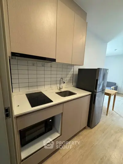 Modern compact kitchen with sleek cabinetry and built-in appliances in a stylish apartment.