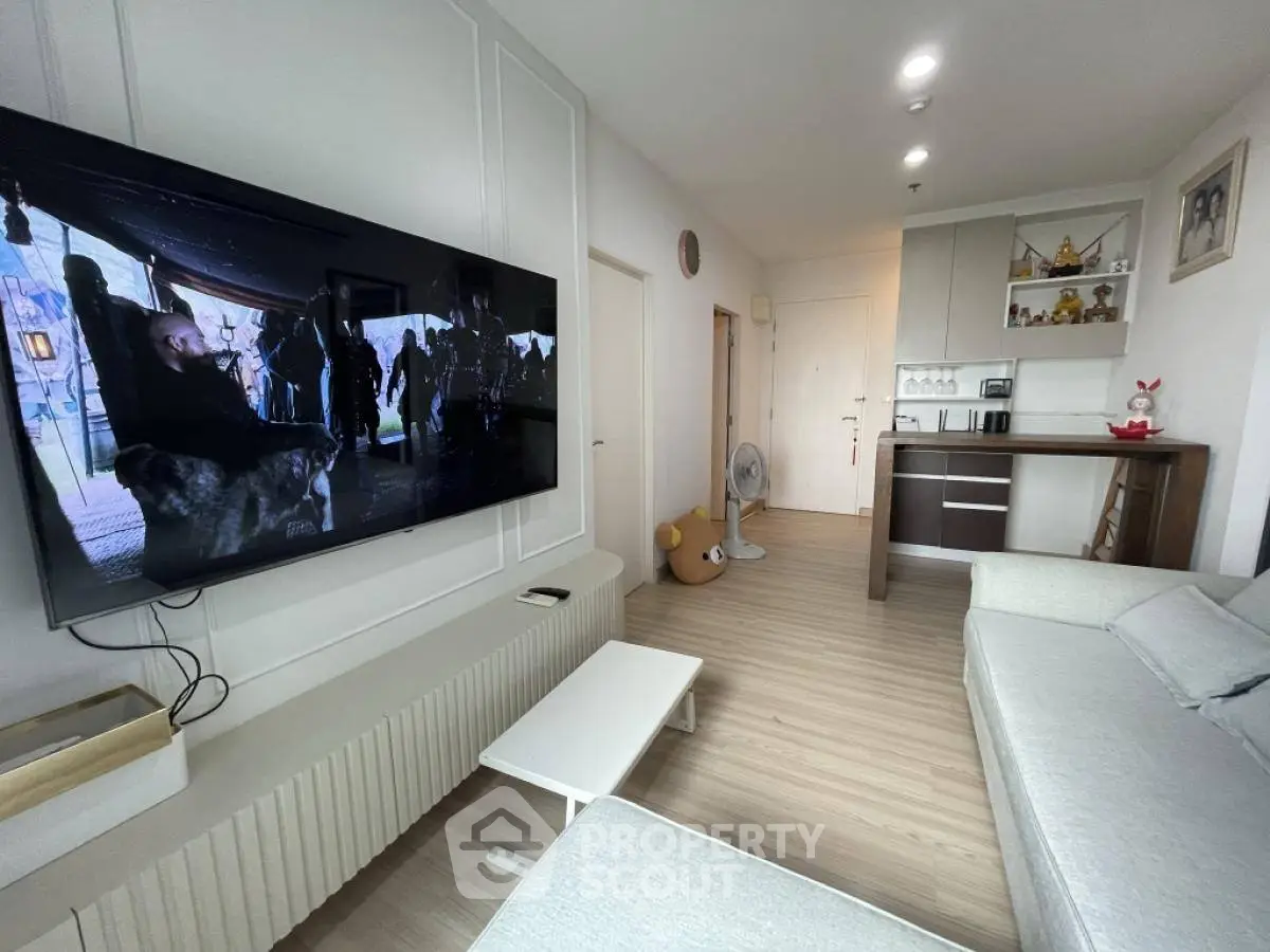 Modern living room with wall-mounted TV and sleek furniture in a cozy apartment.