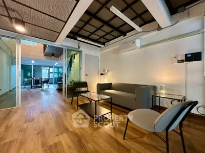 Modern living room with stylish furniture and open layout, featuring wooden flooring and contemporary lighting.