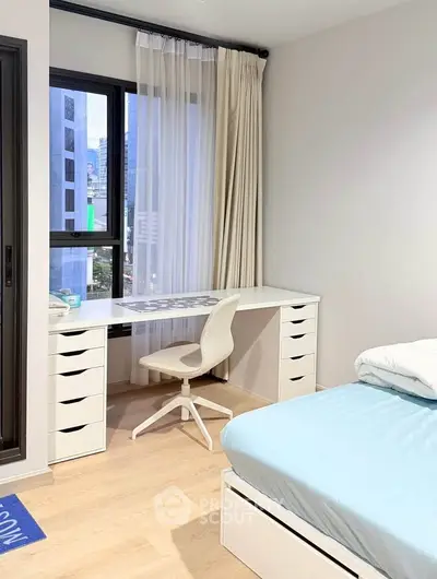 Modern bedroom with city view, featuring a sleek white desk and comfortable chair, perfect for work or study.