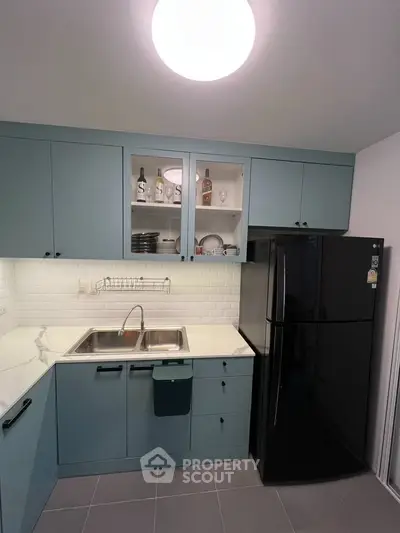 Modern kitchen with sleek blue cabinets and black fridge