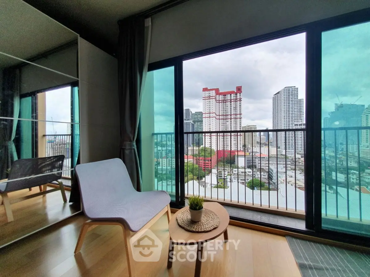 Modern apartment with stunning city view from balcony, featuring stylish chair and small table.