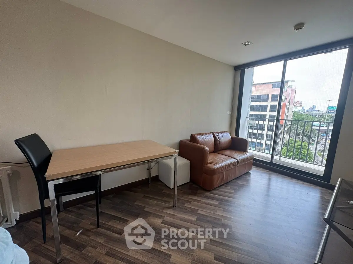 Modern living room with city view, featuring a leather sofa and sleek dining table.