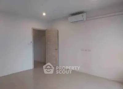 Spacious empty room with air conditioning and open door in modern apartment.