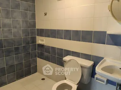 Modern bathroom with blue and white tiles, featuring a toilet and sink.