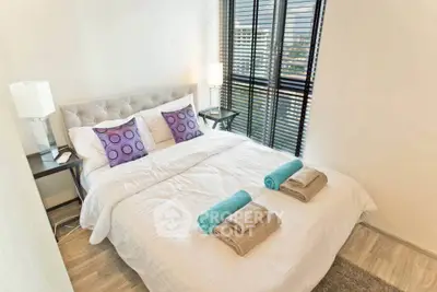 Modern bedroom with stylish decor and natural light, featuring a cozy bed and elegant furnishings.