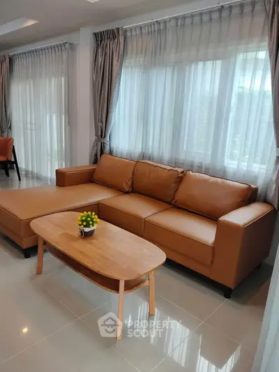 Spacious living room with modern brown leather sofa and elegant curtains