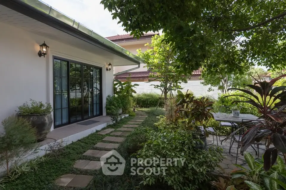 Charming garden view with lush greenery and patio seating in a serene residential setting.