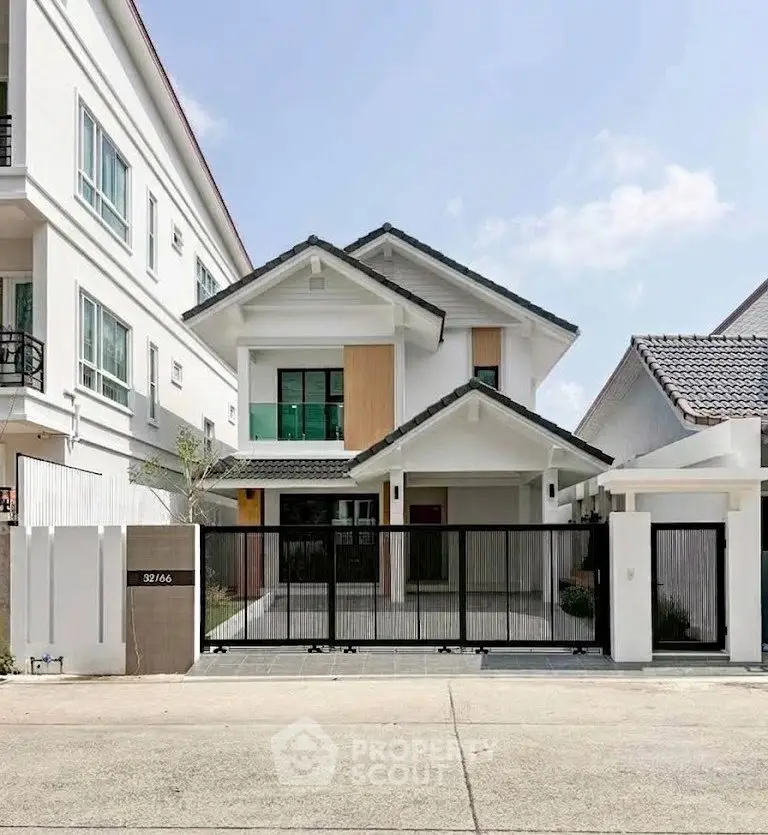 Modern two-story house with sleek design and gated entrance in a suburban neighborhood.