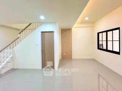 Spacious modern living room with sleek tile flooring and staircase, perfect for contemporary living.