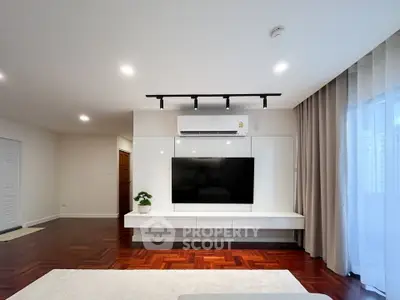 Spacious modern living room with sleek TV setup and elegant hardwood flooring.
