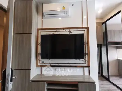 Modern living room with wall-mounted TV and air conditioning unit in stylish apartment.