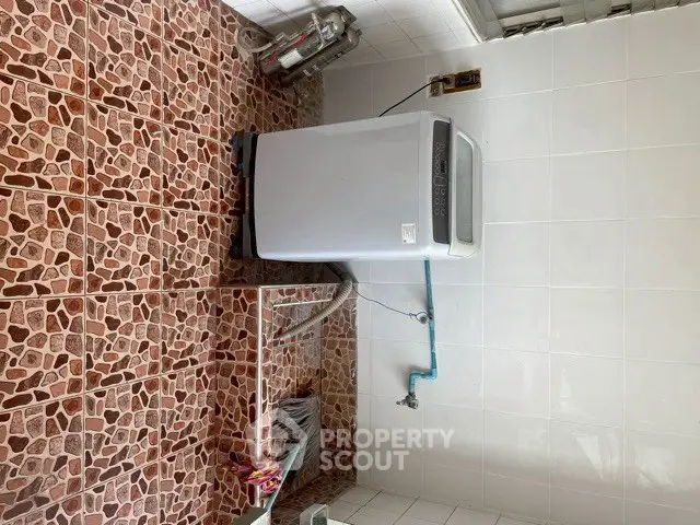 Spacious laundry area with modern washing machine and tiled flooring