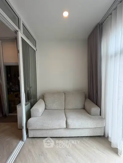 Cozy small living area with a plush sofa and large windows, perfect for relaxation.