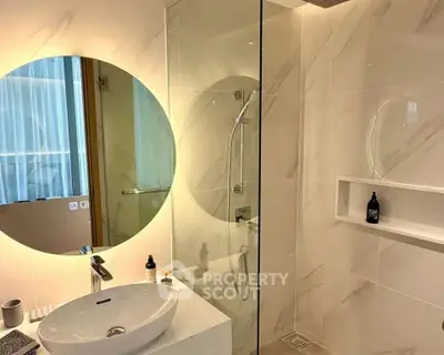 Modern bathroom with round mirror and glass shower enclosure