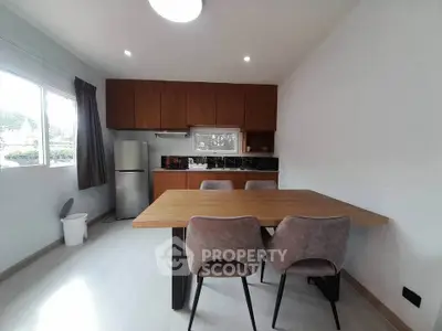 Modern kitchen with dining area, featuring sleek cabinetry and ample natural light.