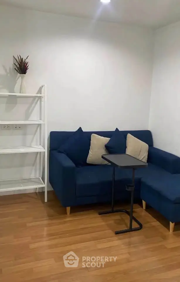 Cozy living room with blue sofa and wooden flooring