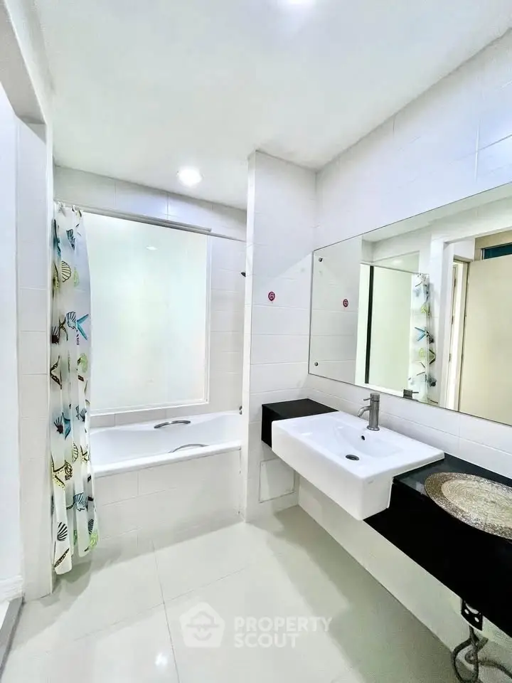 Modern bathroom with sleek white tiles and bathtub in a stylish apartment.