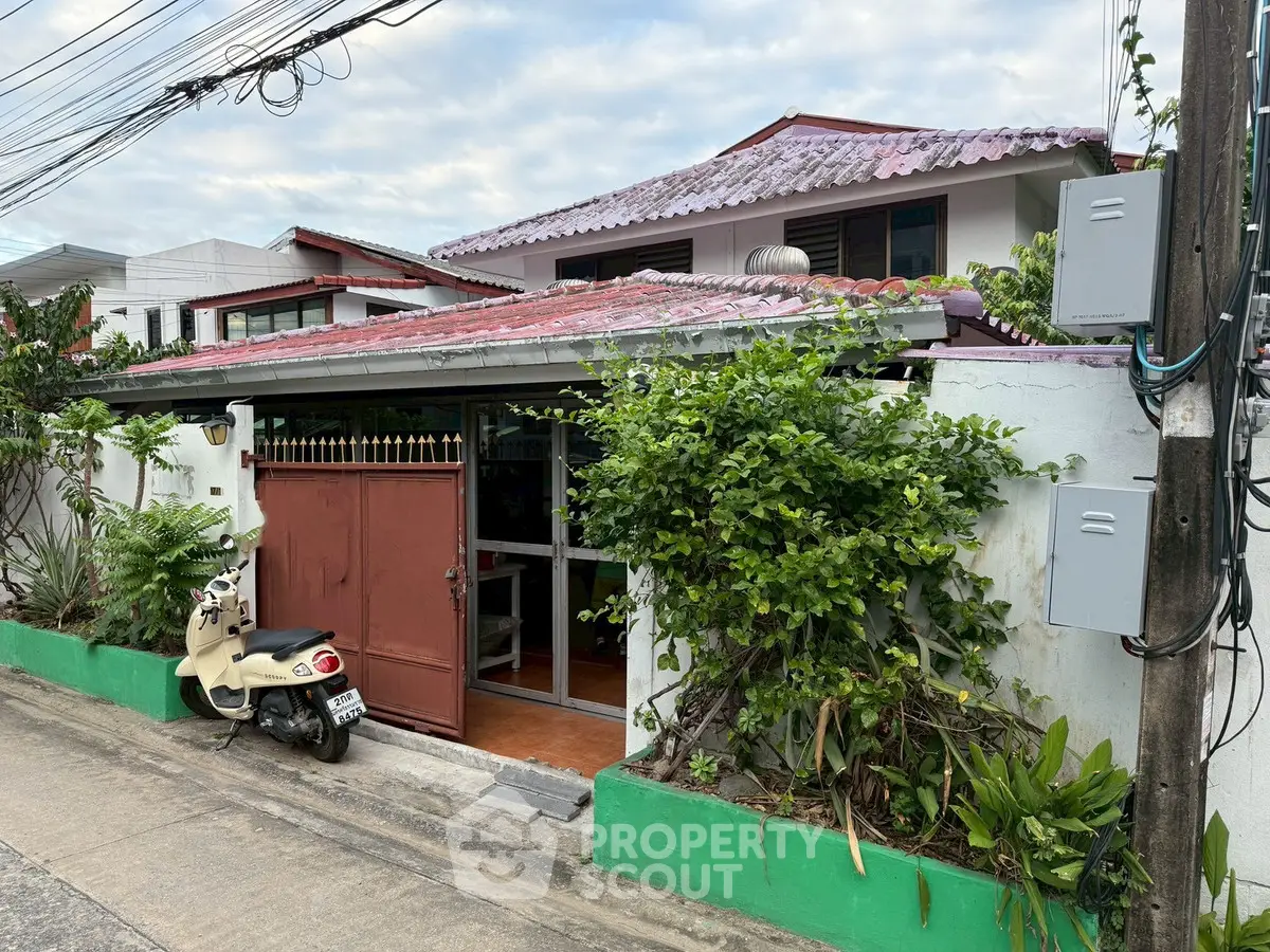 Charming suburban house with lush greenery and secure gated entrance.