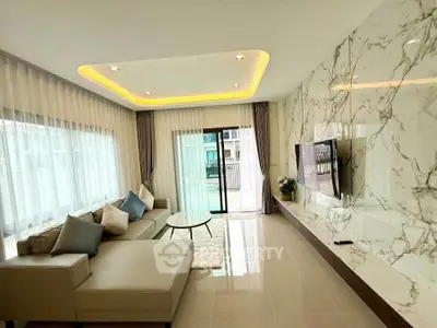 Luxurious living room with modern decor and large windows, featuring a stylish sectional sofa and wall-mounted TV.