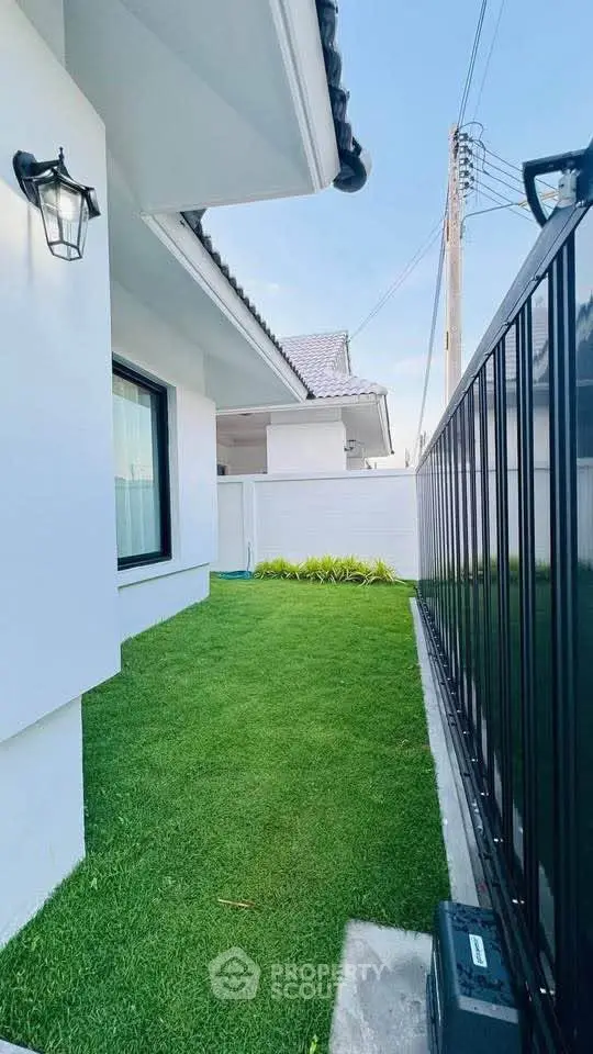 Charming modern home exterior with lush green lawn and sleek black fence, perfect for privacy and curb appeal.
