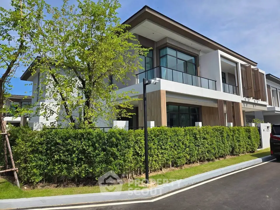 Modern luxury house with large windows and lush greenery in a serene neighborhood.