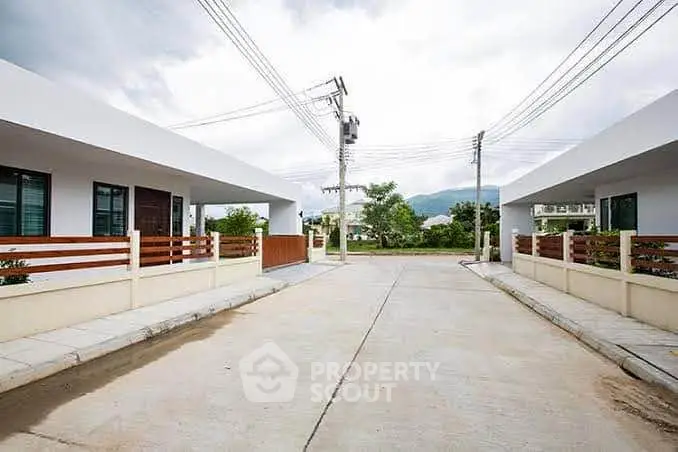 Modern residential street with contemporary homes and scenic mountain backdrop.