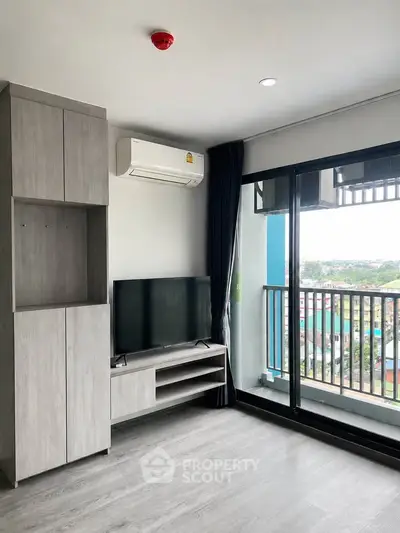 Modern living room with large windows and balcony offering a stunning city view, featuring sleek furniture and air conditioning.