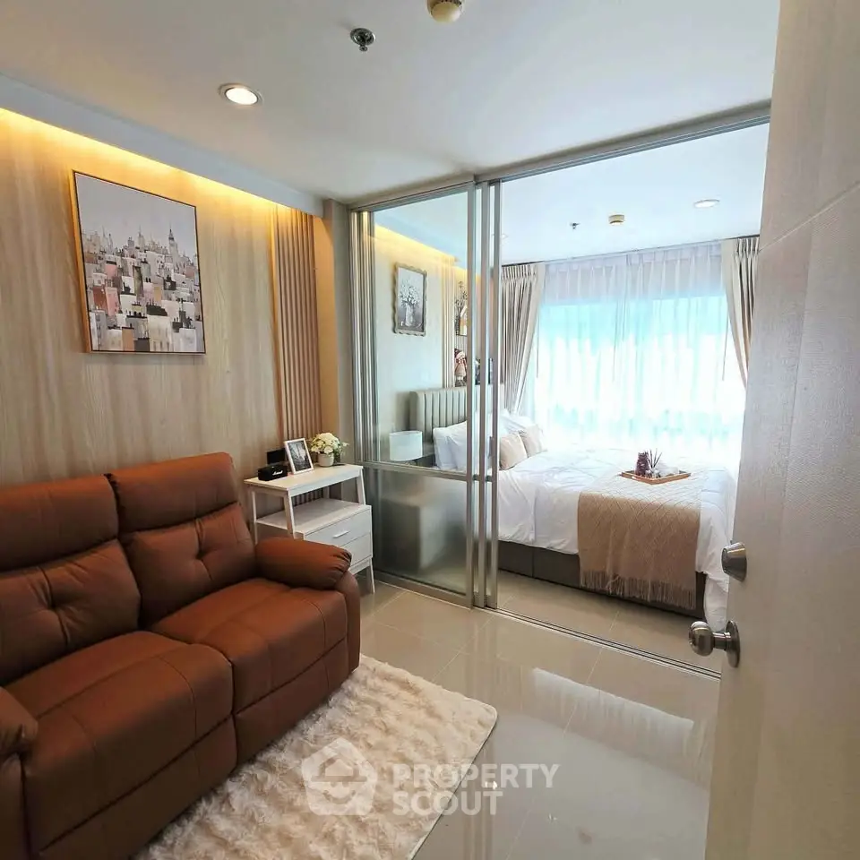 Modern apartment with cozy living room and elegant bedroom separated by glass doors.