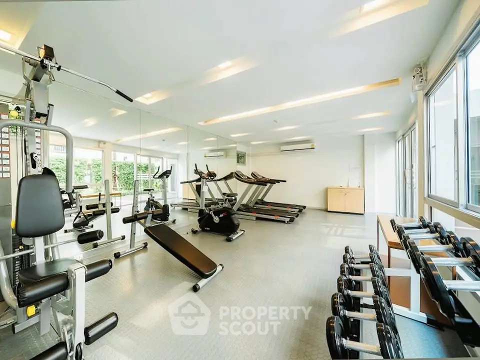 Spacious modern gym with state-of-the-art equipment and large windows for natural light.
