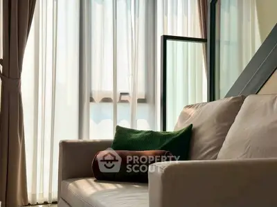 Cozy living room with elegant sofa and large windows offering natural light